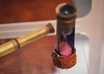 Antique hourglass and telescope for observation from the ship. Old objects of the 18th century era, reenactment of events