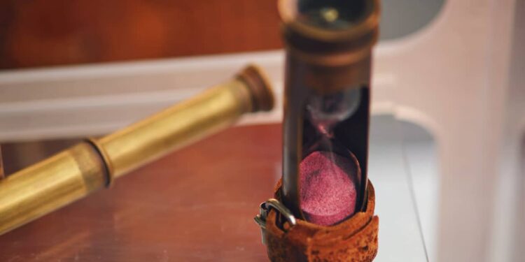 Antique hourglass and telescope for observation from the ship. Old objects of the 18th century era, reenactment of events