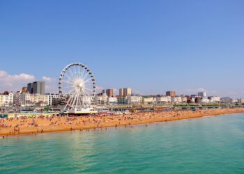 Panoramic view of Brighton Beach. Brighton wheel and hotels. Crowded with people on sunny day.