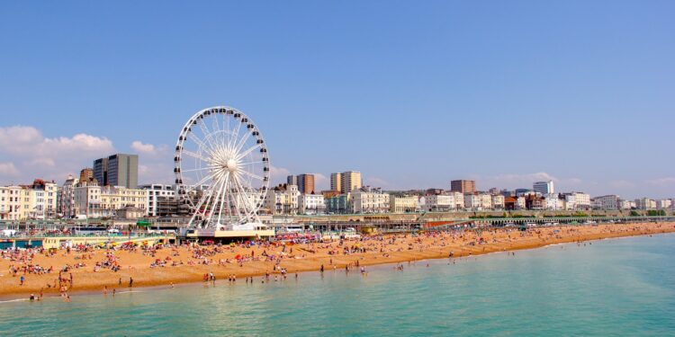 Panoramic view of Brighton Beach. Brighton wheel and hotels. Crowded with people on sunny day.